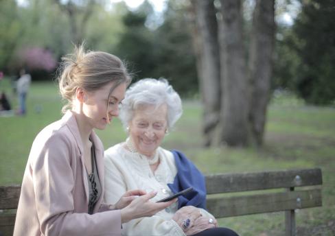 Elderly woman sitting on bench with a younger adult woman