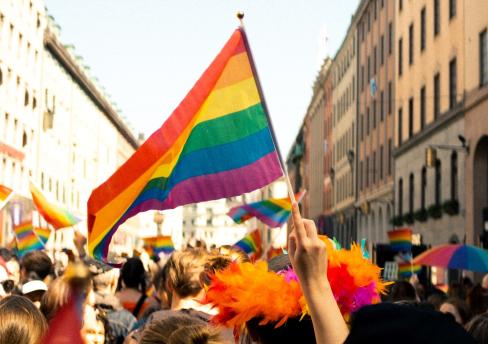Person holding LGBTIQA+ pride flag