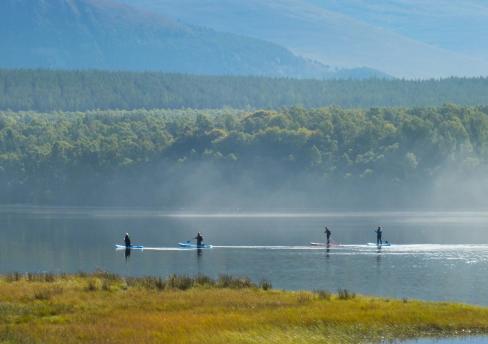 People paddle boarding on a loch 