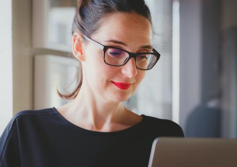 Woman wearing black framed glasses sitting at laptop
