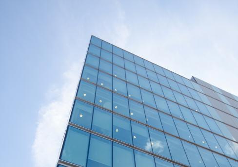 Glass office building against backdrop of blue sky
