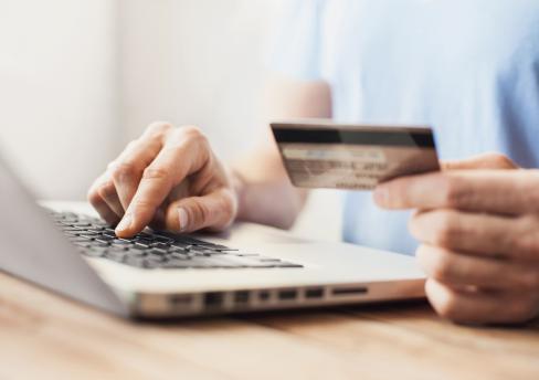Person making online purchase with bank card in hand
