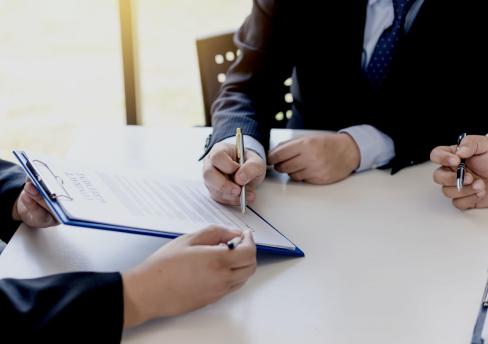 Person's hand holding pen signing a legal document 