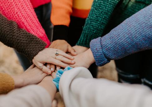 Group of people in a circle putting their hands together in the middle