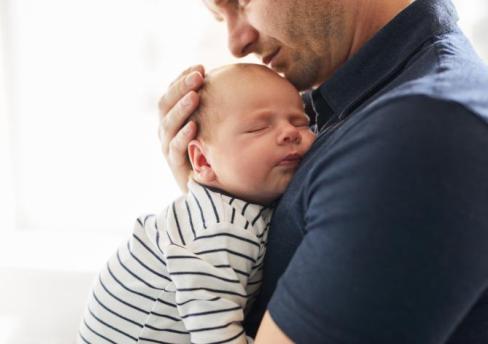 Man holding young baby to chest